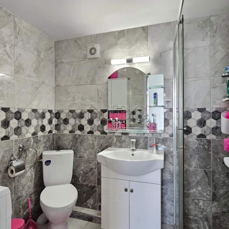 Bright bathroom with white fixtures and stylish tiled walls in a renovated detached house.