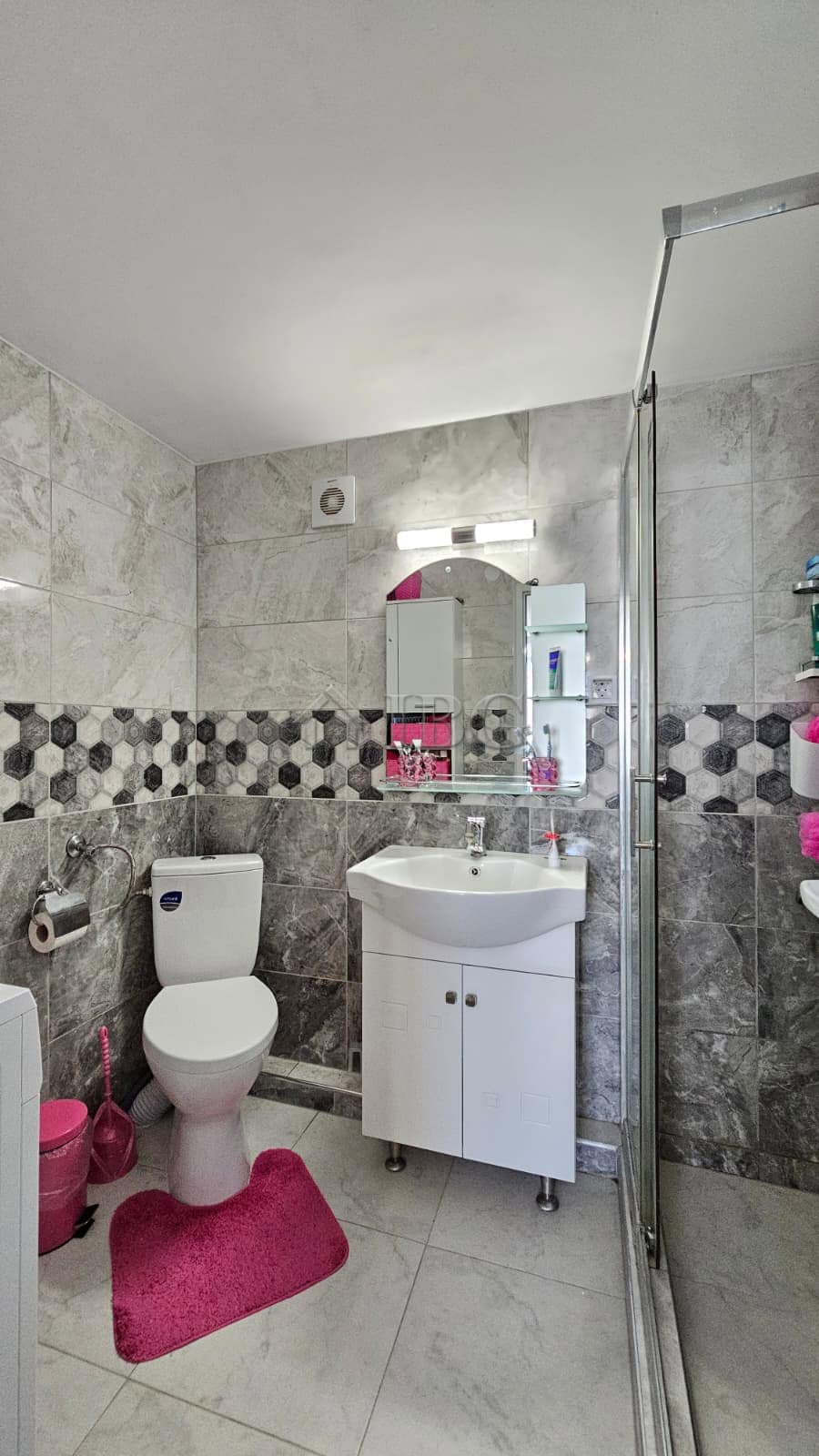 Bright bathroom with white fixtures and stylish tiled walls in a renovated detached house.