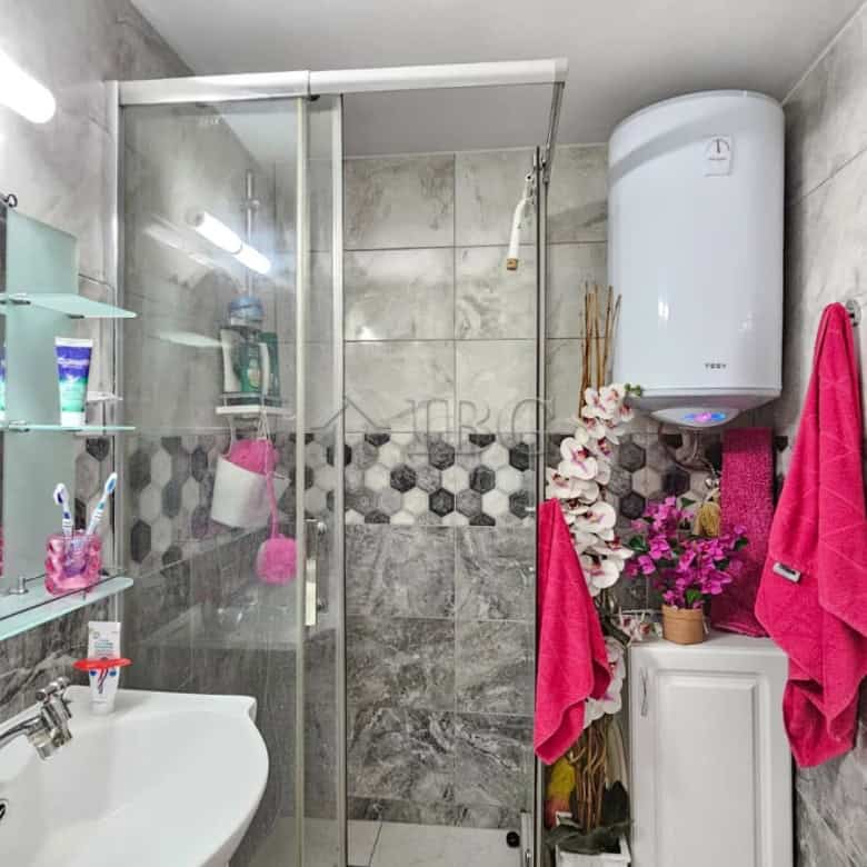 Bright bathroom with glass shower enclosure and contemporary fixtures.