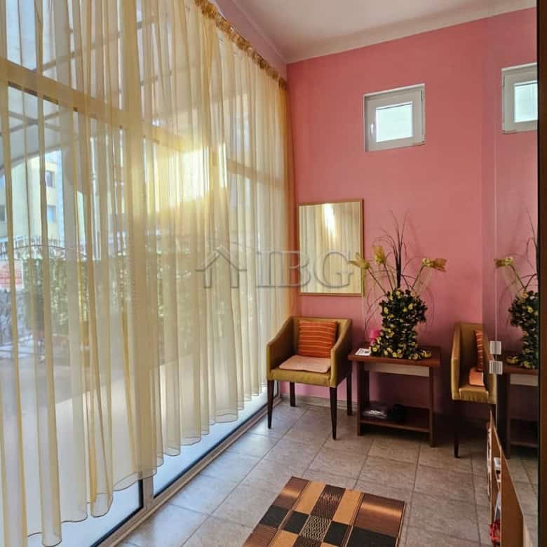 Sunlit interior with pink walls, large windows with sheer curtains, and cozy seating area in a comme.