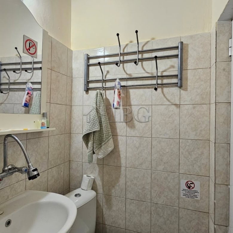 Small bathroom with sink, toilet, and wall hooks in Sunny Beach commercial property.