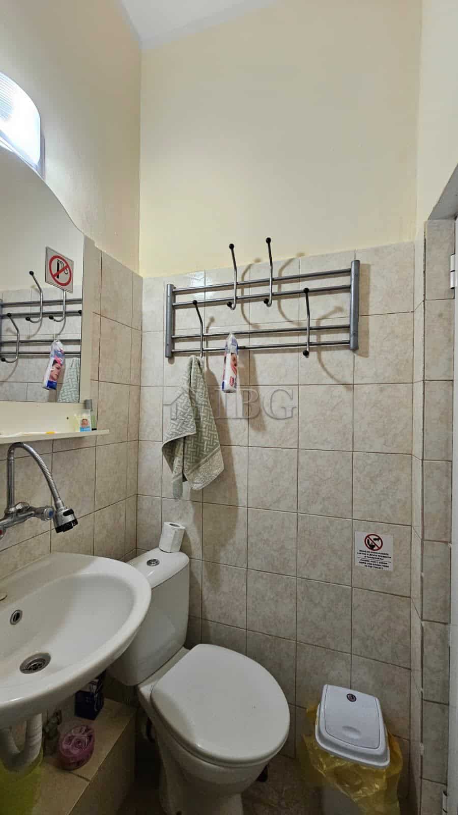 Small bathroom with sink, toilet, and wall hooks in Sunny Beach commercial property.