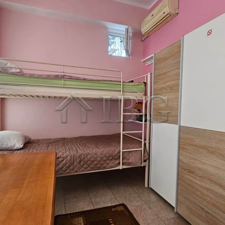 Cozy bedroom featuring a bunk bed, wardrobe, and air conditioning unit in a sunny beach area.