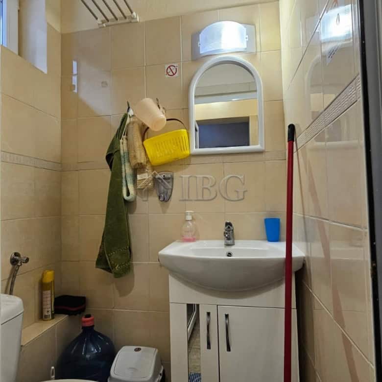 Small bathroom with sink, toilet, and cleaning supplies in Sunny Beach commercial property.