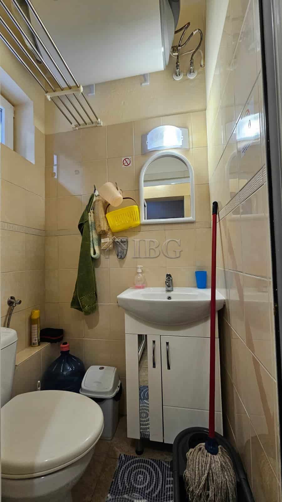 Small bathroom with sink, toilet, and cleaning supplies in Sunny Beach commercial property.