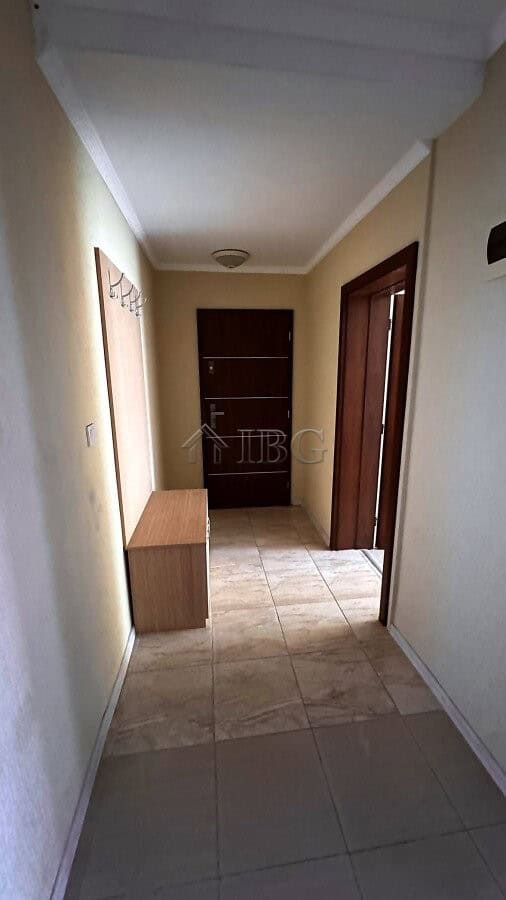 Interior view of a hallway in a 2-bedroom apartment with tiled flooring and wooden doors in Sunny Be.