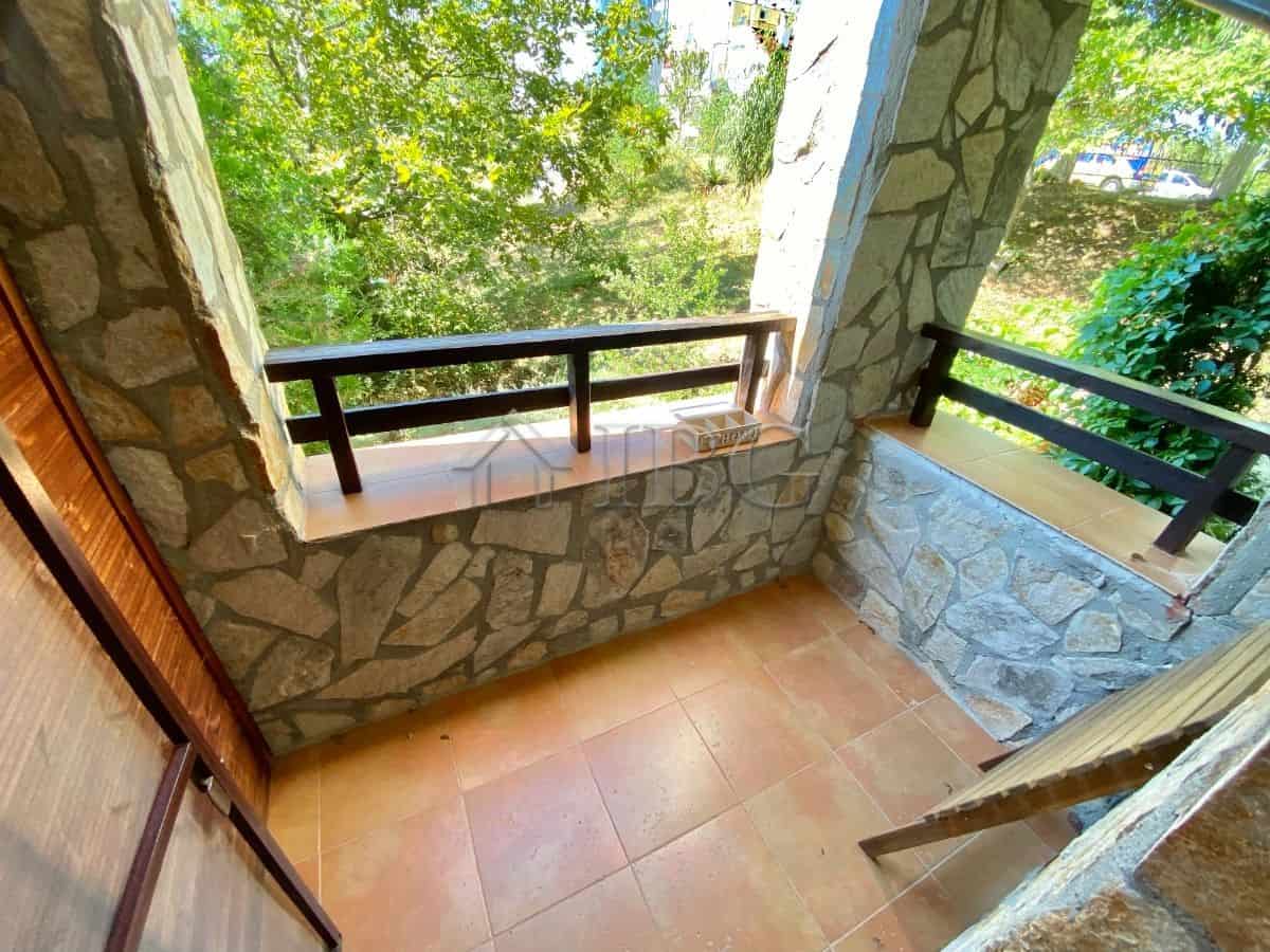 Bright balcony with stone walls and lush greenery view.
