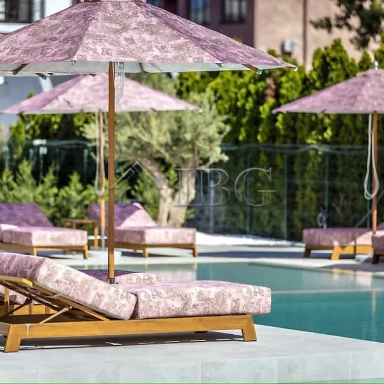 Luxurious poolside lounge with sunbeds and umbrellas in a contemporary complex.
