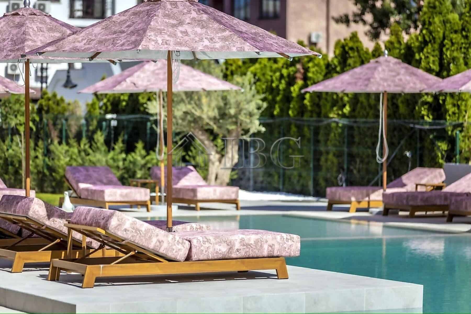 Luxurious poolside lounge with sunbeds and umbrellas in a contemporary complex.