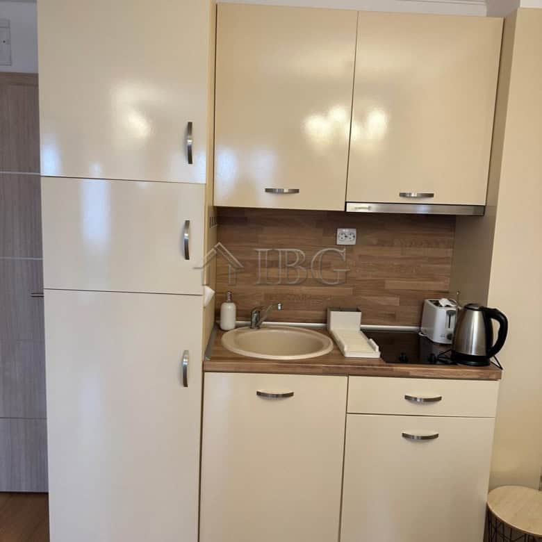 Compact kitchen with beige cabinets and modern appliances in Sunny Beach apartment.