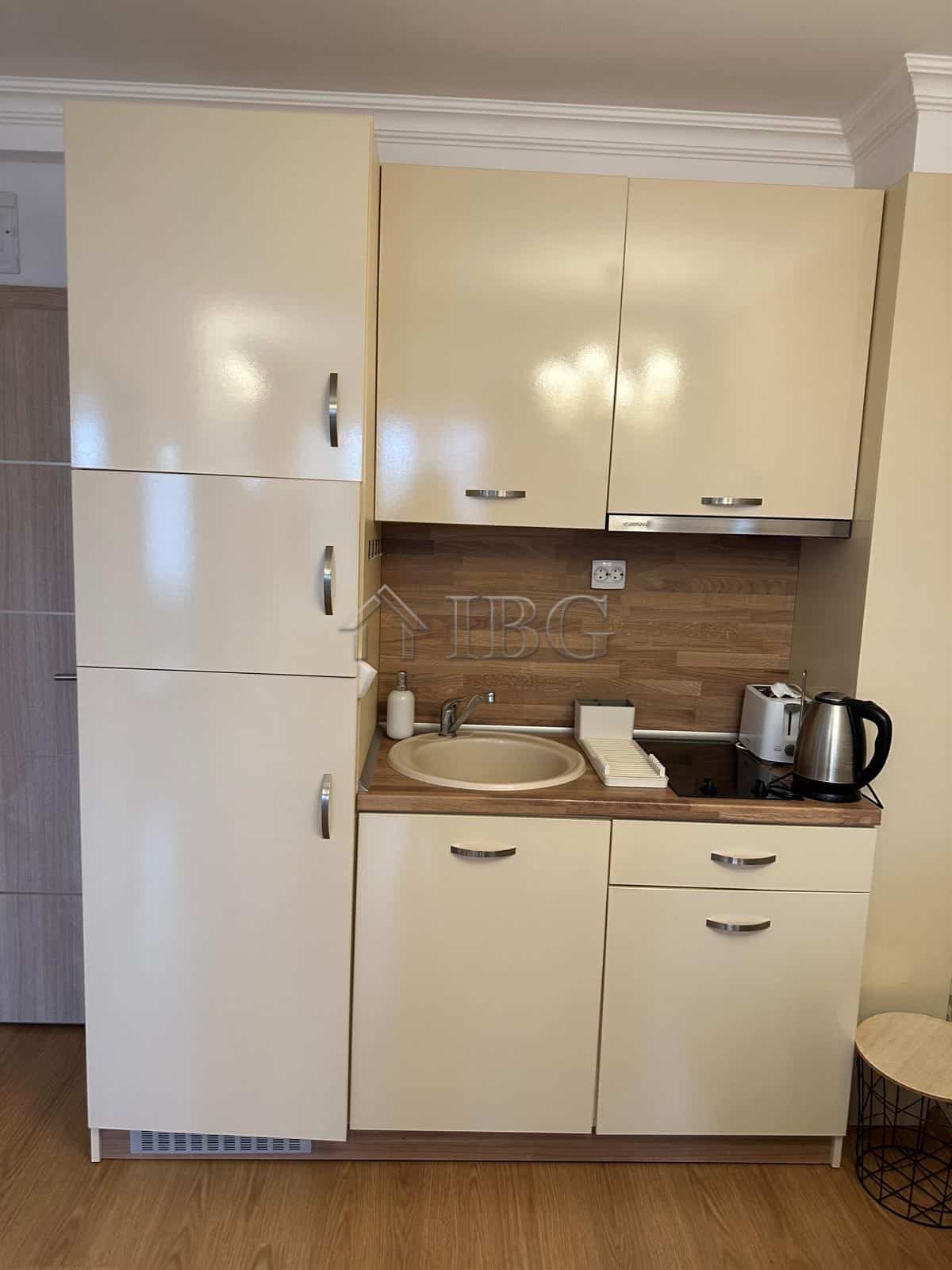 Compact kitchen with beige cabinets and modern appliances in Sunny Beach apartment.
