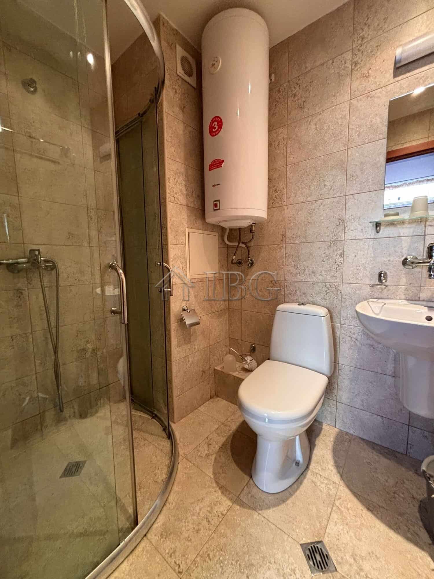 Small bathroom with shower, toilet, and water heater in Dawn Park, Sunny Beach.