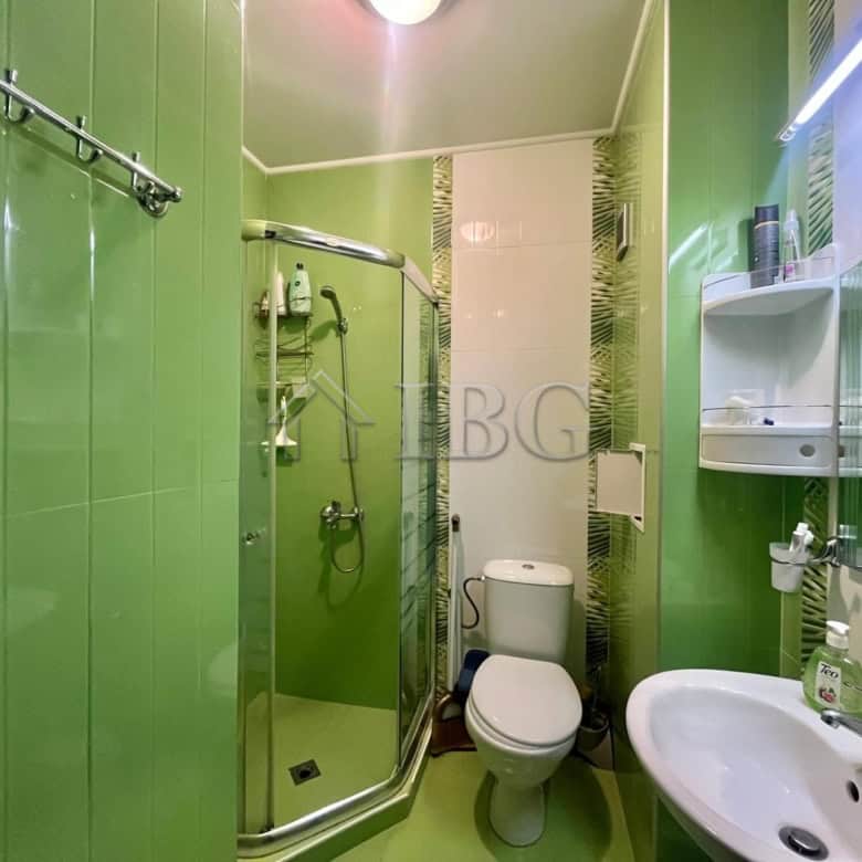 Bright green bathroom with shower, toilet, and sink in Odyssey, Nessebar.