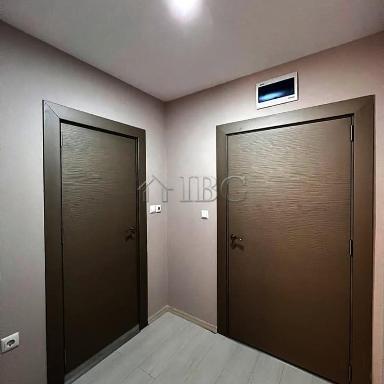 Interior view of two modern apartment doors in a new complex with neutral walls and ceiling lighting.