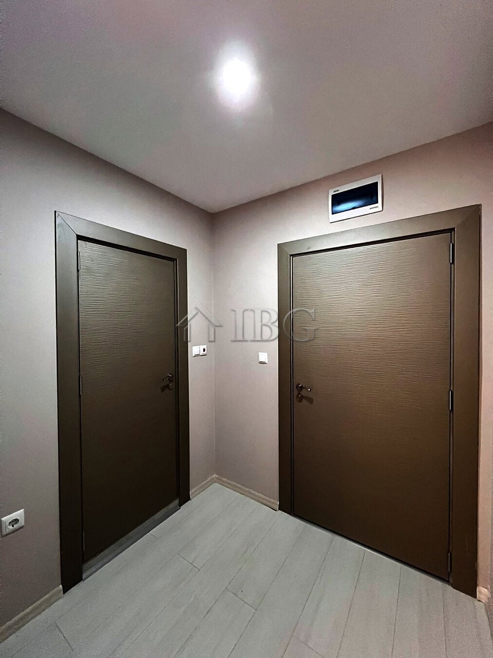 Interior view of two modern apartment doors in a new complex with neutral walls and ceiling lighting.