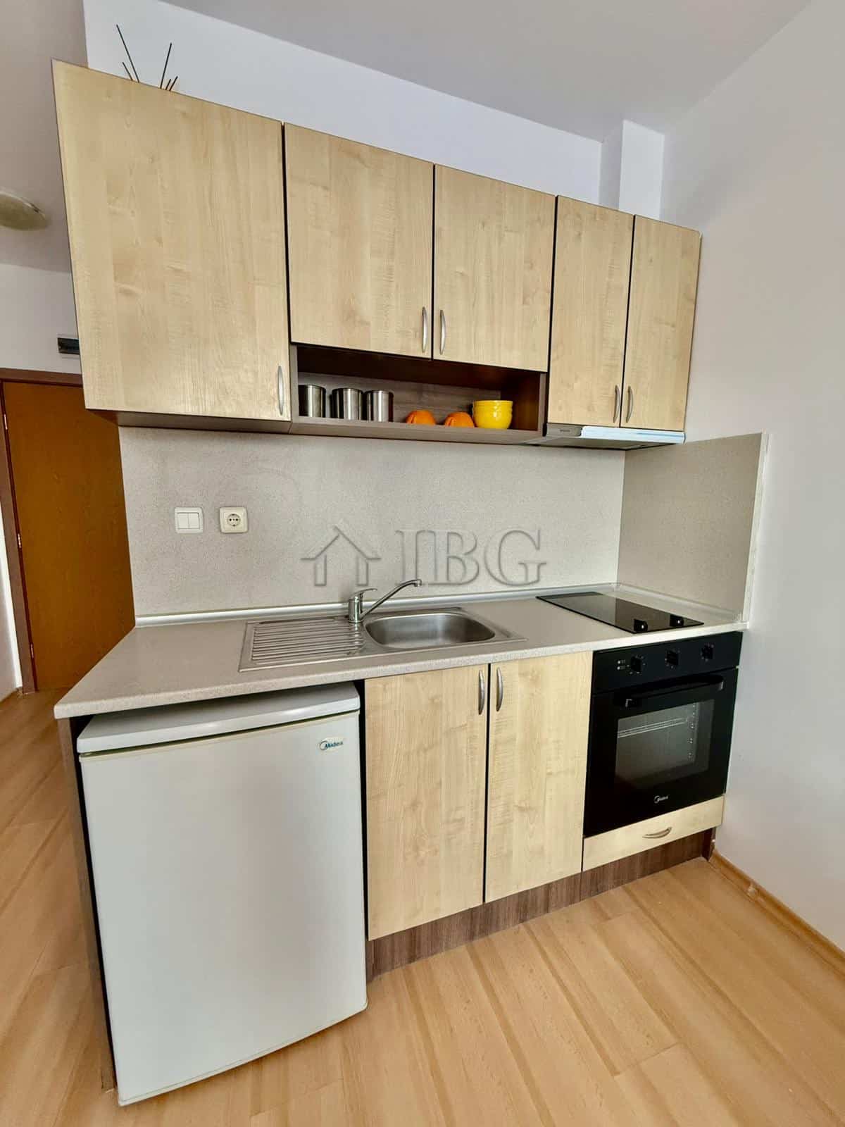 Furnished studio kitchen with modern cabinets, sink, stove, and mini fridge in Sunny Day 3, Sunny Be.