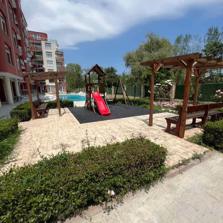 Outdoor playground with slide and swings in a residential complex.