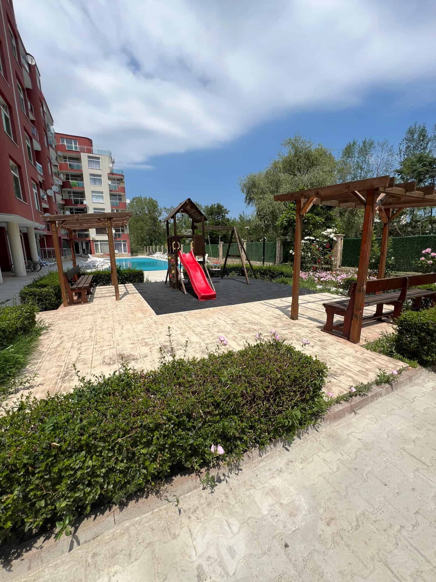 Outdoor playground with slide and swings in a residential complex.