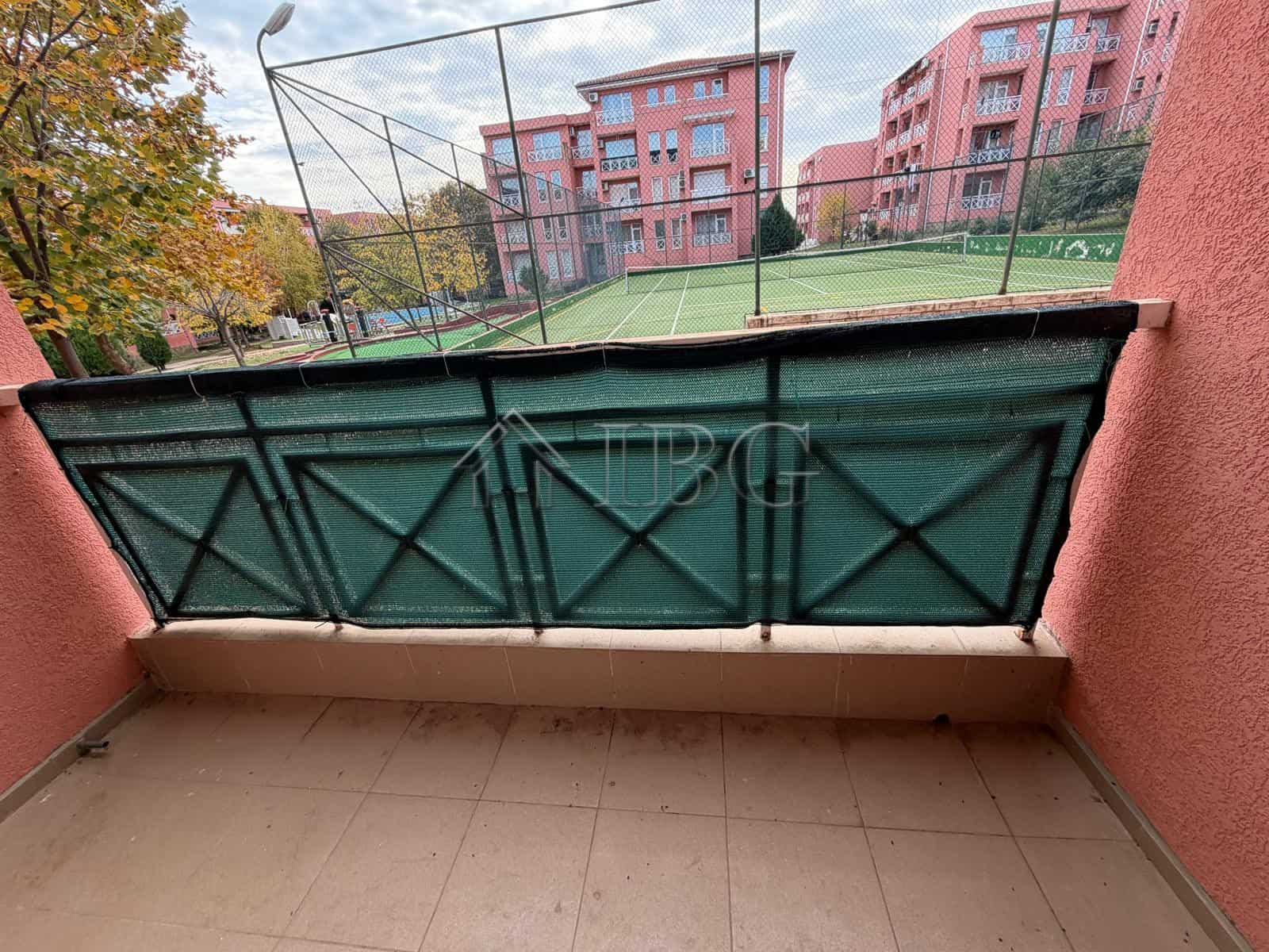 Balcony overlooking a tennis court and park in sunny beach area. Perfect for relaxing and enjoying o.
