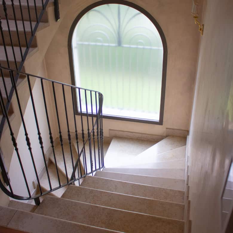 Spacious staircase featuring a large arched window allowing ample natural light into the home.