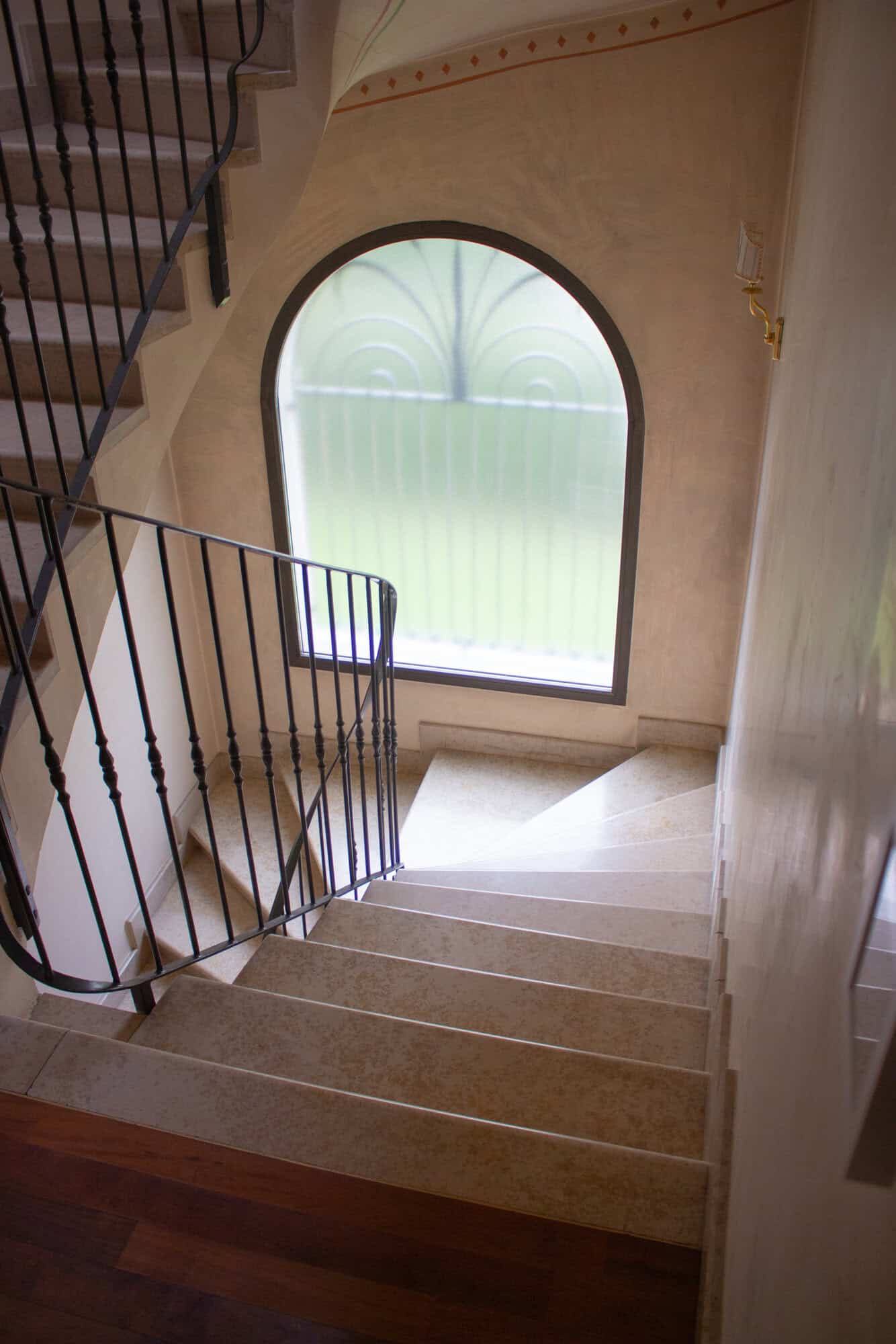 Spacious staircase featuring a large arched window allowing ample natural light into the home.