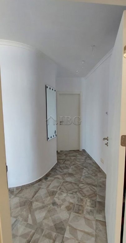 Interior view of a bright, minimalist apartment corridor with white walls and tiled flooring.