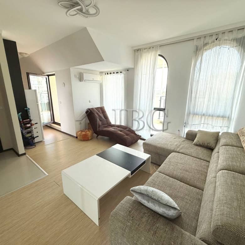 Bright living room with sofa, armchair, and large windows with curtains.