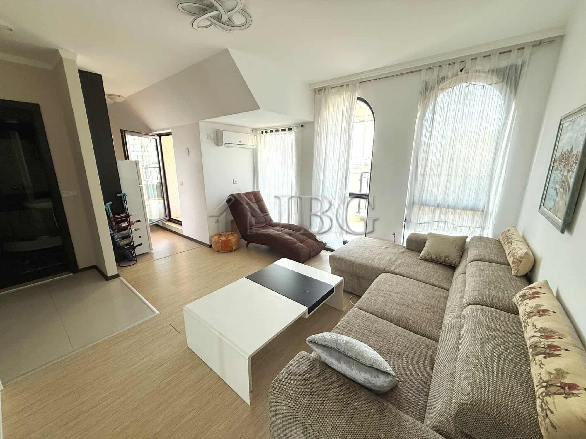 Bright living room with sofa, armchair, and large windows with curtains.