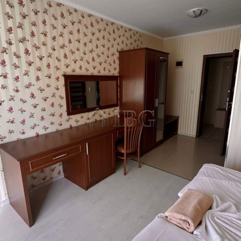 Comfortable bedroom featuring a wooden desk, wardrobe, and a partial view of the sea from Sunny Beac.