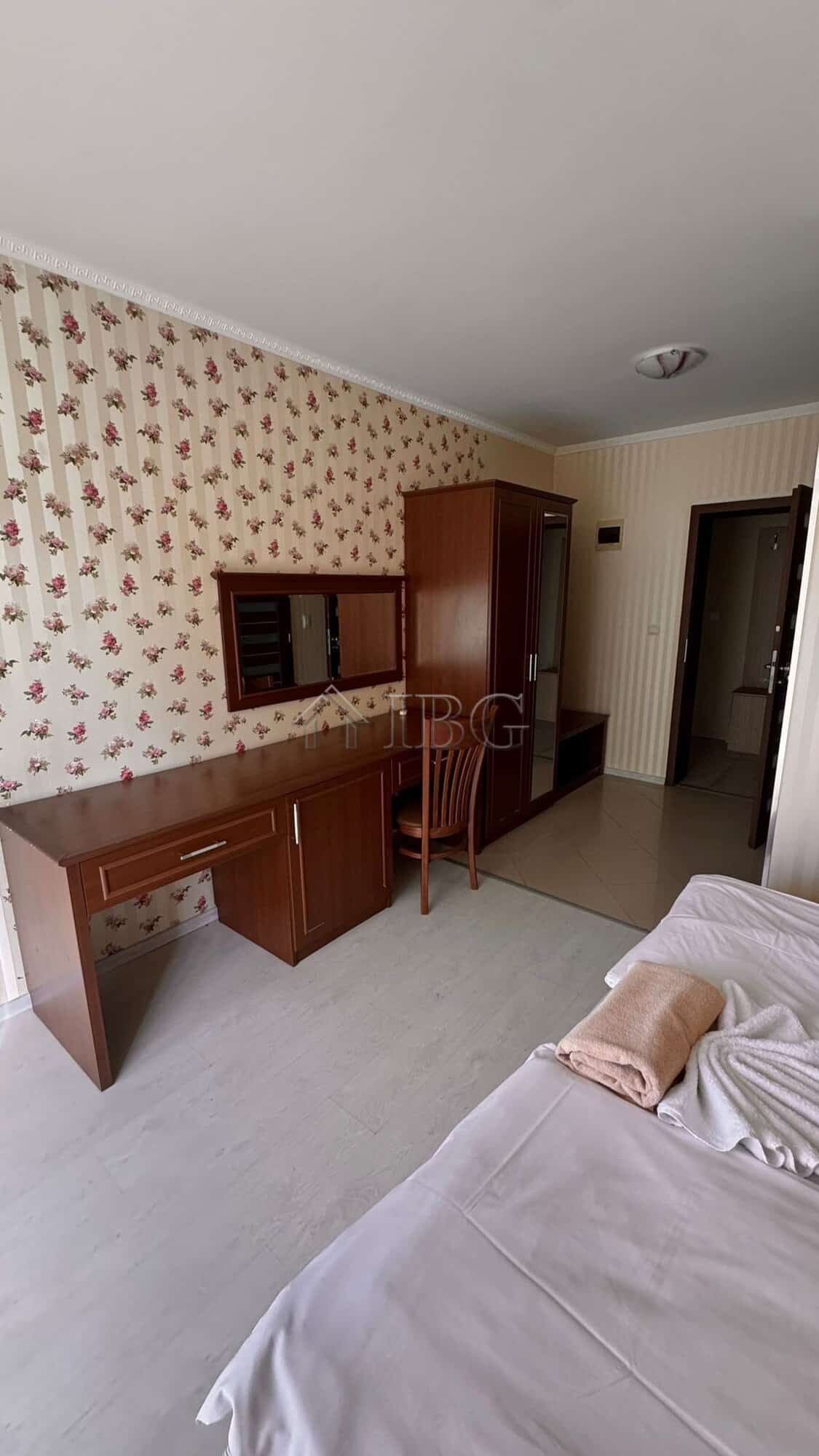 Comfortable bedroom featuring a wooden desk, wardrobe, and a partial view of the sea from Sunny Beac.