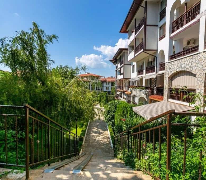 Apartment with balconies overlooking lush garden and pathway.