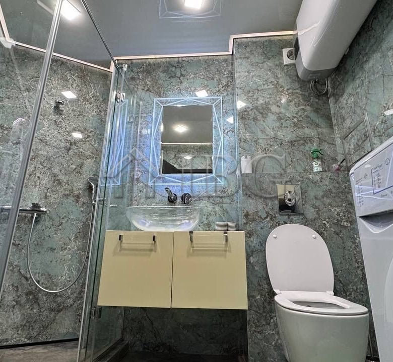 Bathroom with shower, toilet, and washing machine in a modern apartment.