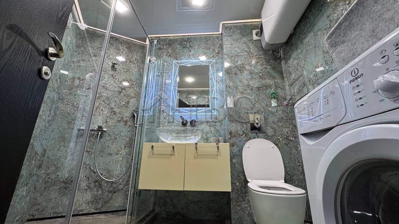 Bathroom with shower, toilet, and washing machine in a modern apartment.