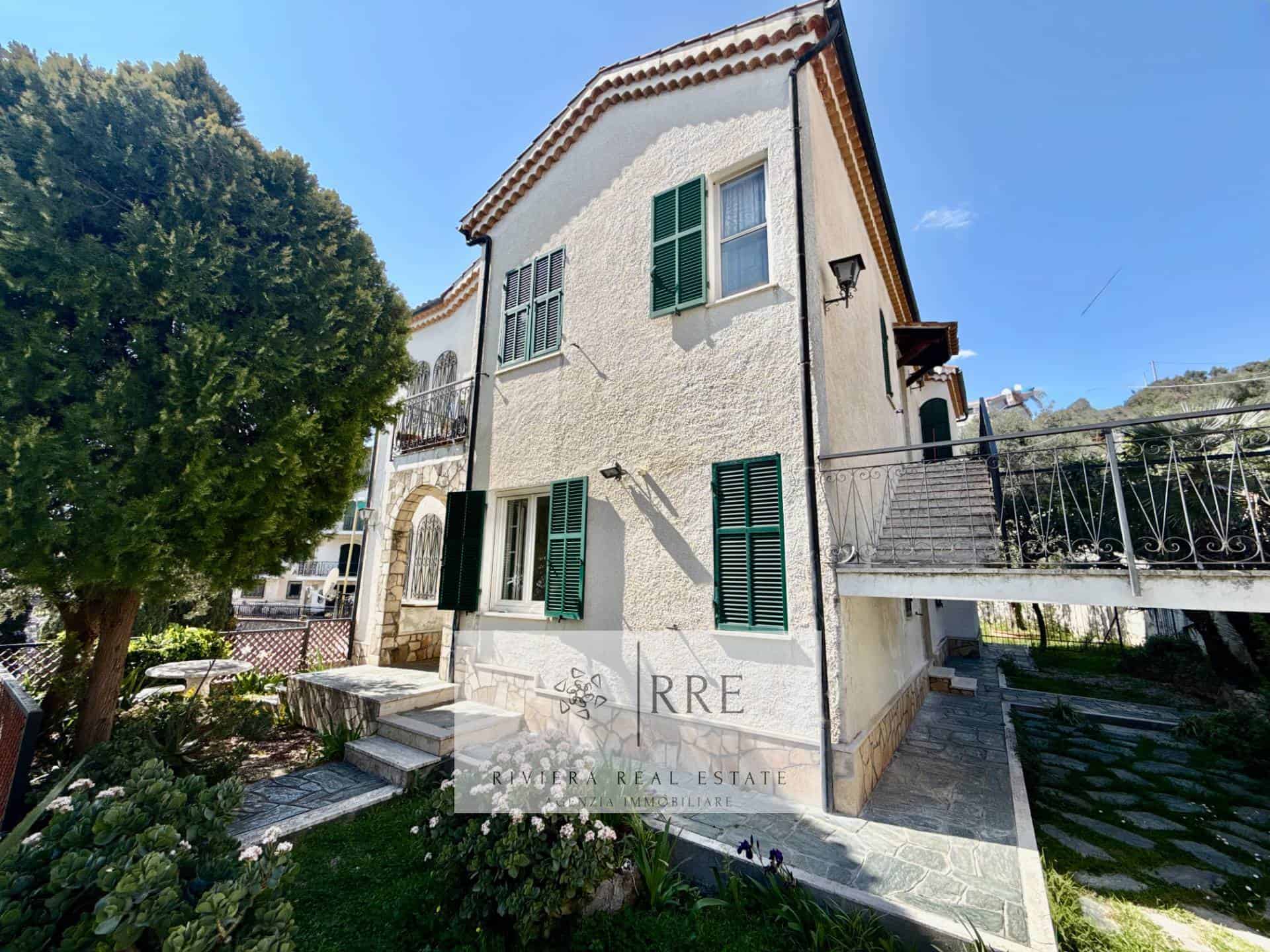 Beautiful Mediterranean-style villa with lush garden and green shutters.