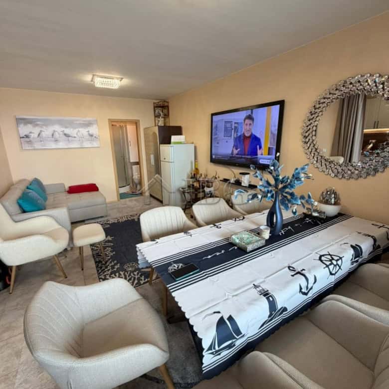 Bright living room with sea view, TV, and stylish furniture in Sunny Beach apartment.