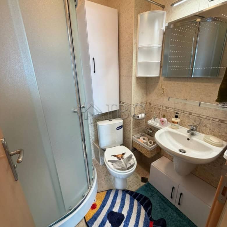 Compact bathroom with shower, toilet, and sink in a seaside apartment.