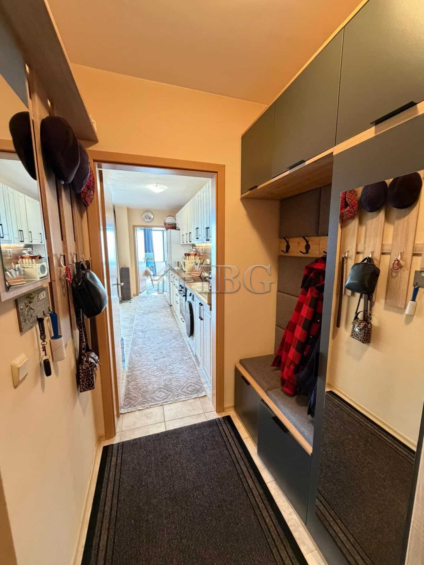 Entrance hall with hooks, shoes, and storage in Sunny Beach apartment.