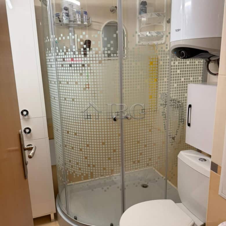 Modern bathroom with glass shower enclosure and essential fixtures.