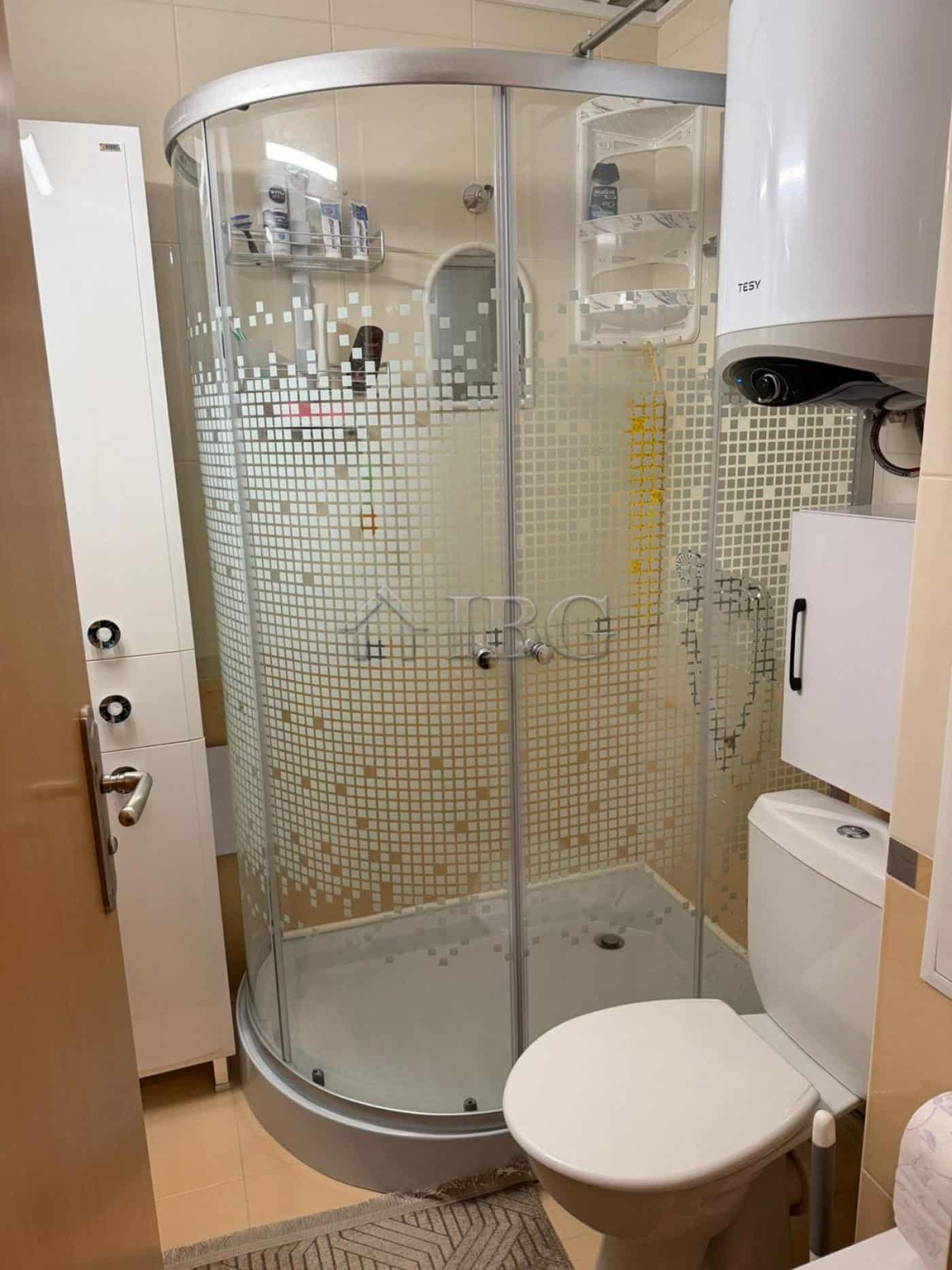 Modern bathroom with glass shower enclosure and essential fixtures.