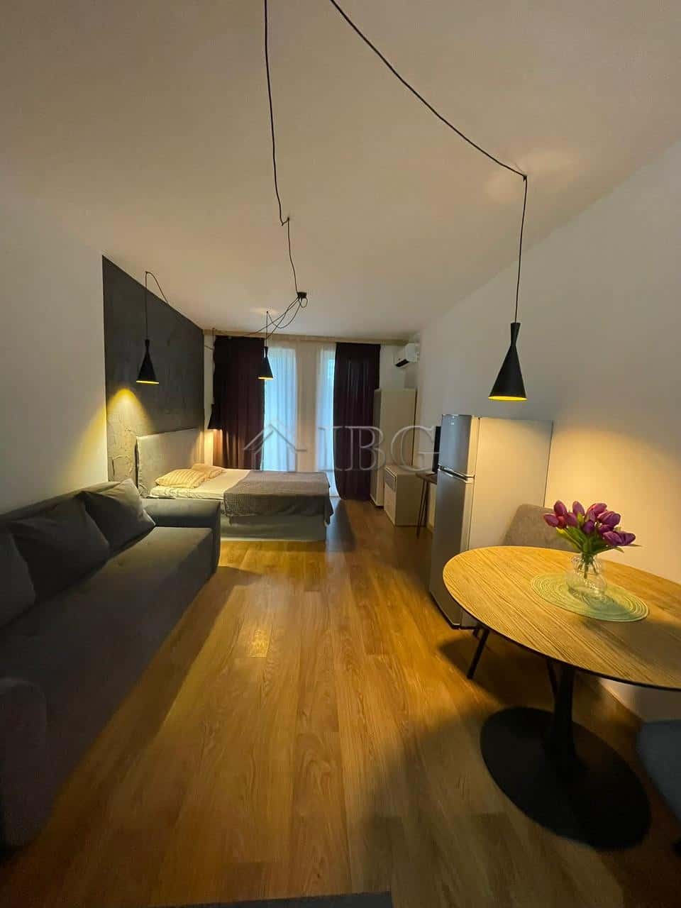 Interior of a studio apartment with a sofa, bed, dining table, and balcony in Sunny View Central, Su.