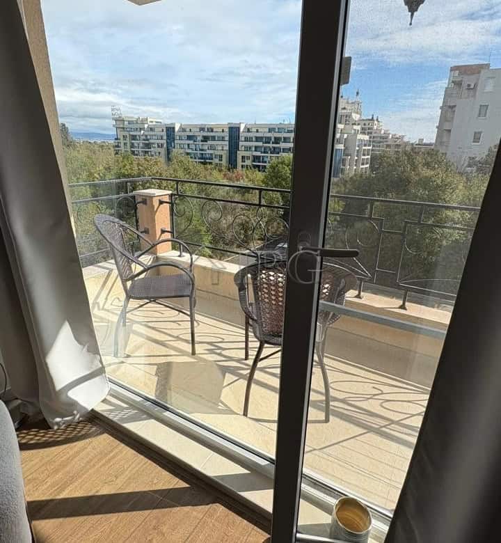 Balcony overlooking Pomorie with chairs, table, and scenic urban landscape.
