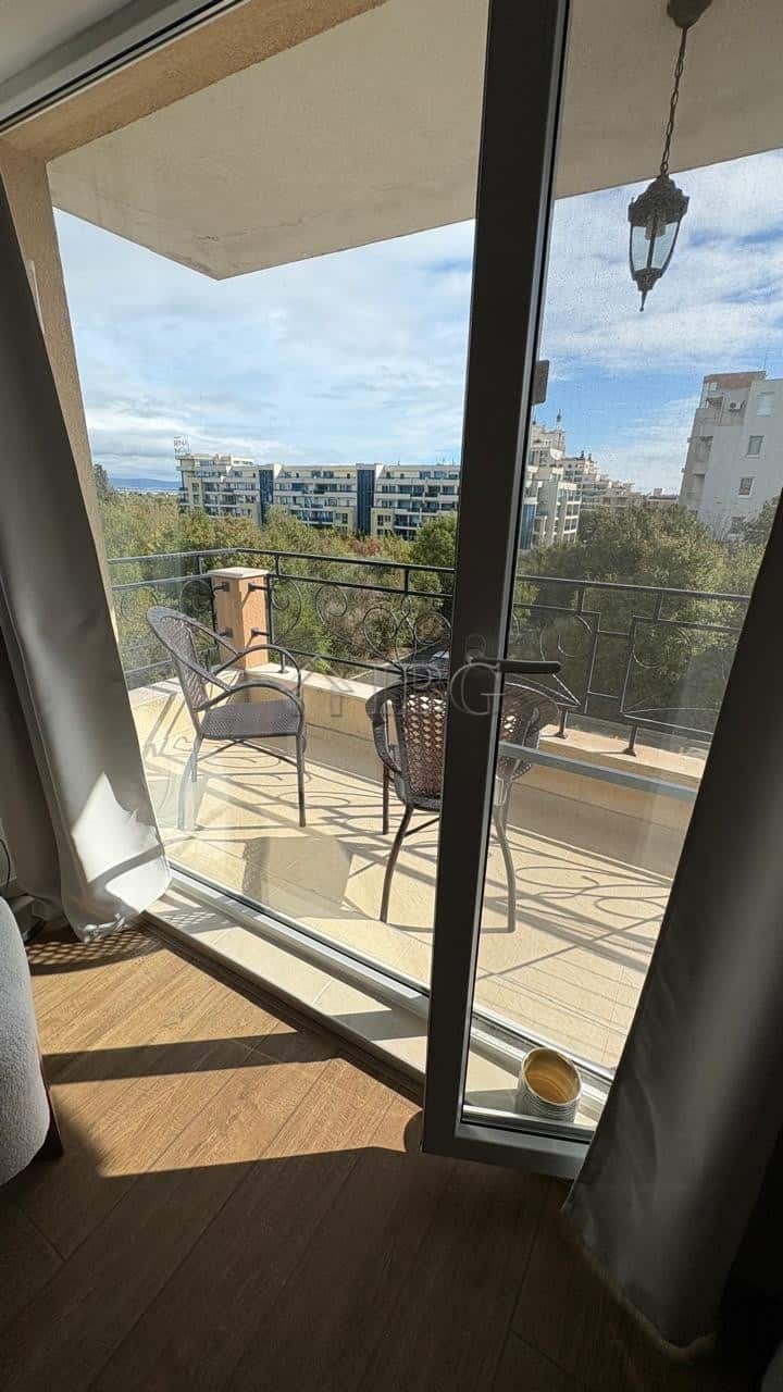 Balcony overlooking Pomorie with chairs, table, and scenic urban landscape.