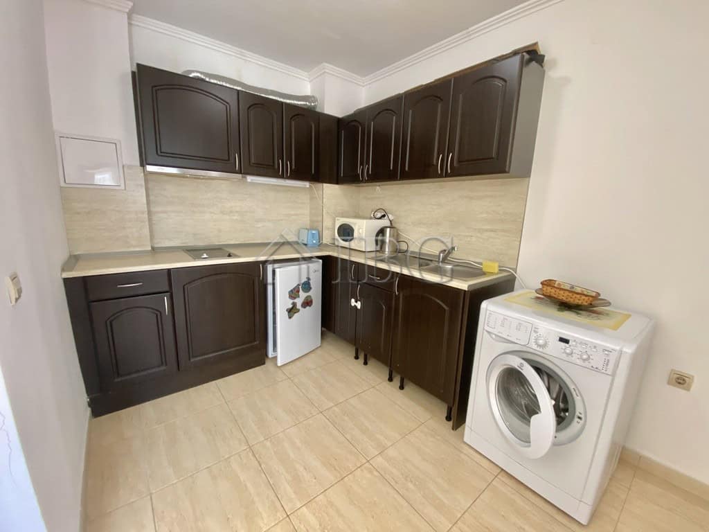 Spacious kitchen featuring dark wood cabinetry, washing machine, and essential appliances in Sveti V.