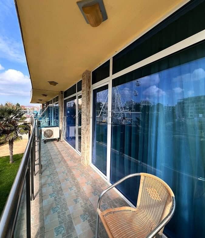 Balcony with glass walls, outdoor chair, and view of the complex in Sunny Beach, Bulgaria.