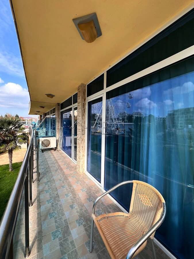 Balcony with glass walls, outdoor chair, and view of the complex in Sunny Beach, Bulgaria.