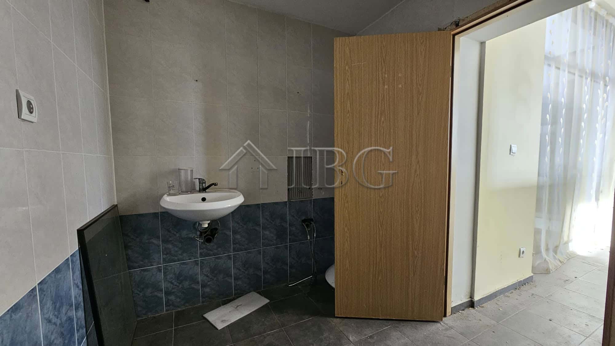 Interior view of a commercial space with a small sink and open door in Sunny Beach.