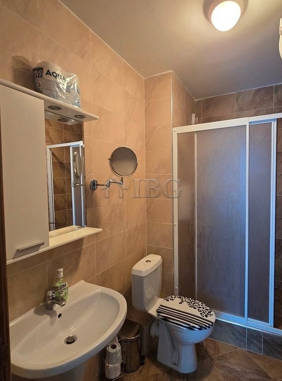 Bathroom with sink, toilet, mirror, and shower enclosure in a contemporary style.