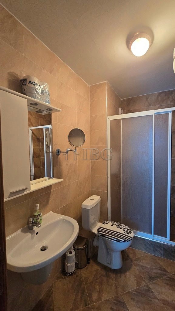 Bathroom with sink, toilet, mirror, and shower enclosure in a contemporary style.