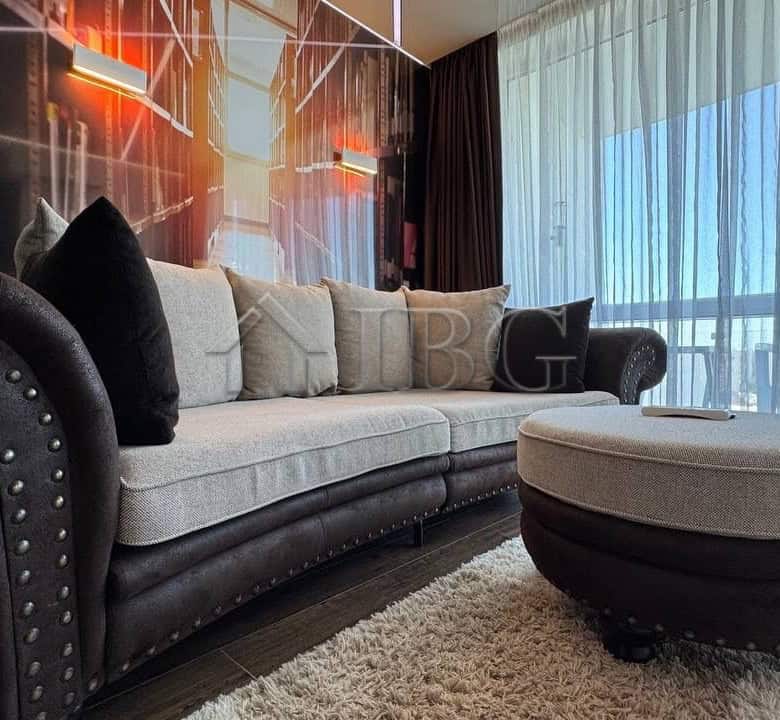 Stylish living room featuring a comfortable sofa, decorative cushions, and a balcony with scenic sea.