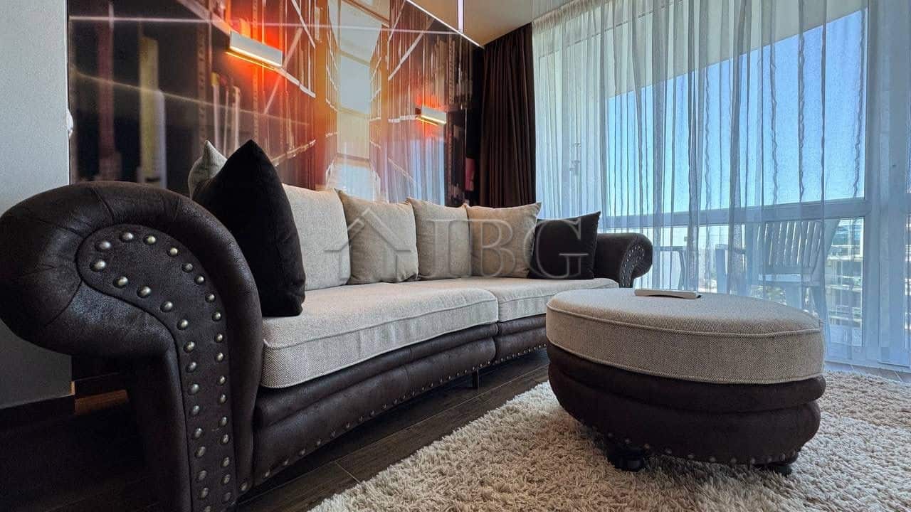 Stylish living room featuring a comfortable sofa, decorative cushions, and a balcony with scenic sea.